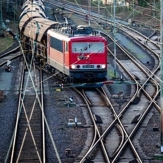 Ein Güterzug fährt über die Gleise eines Rangierbahnhofs. 