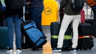 Passagiere warten am Flughafen an einem Check-In-Schalter der Lufthansa. 
