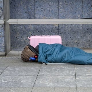 Eine obdachlose Person schläft auf dem Boden. (Symbolbild)