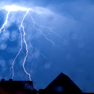 Ein greller Blitz zeichnet sich am dunklen Himmel ab