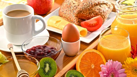Frühstück mit Orangensaft, Ei, Kaffee, Marmelade, Honig, Obst und Käse