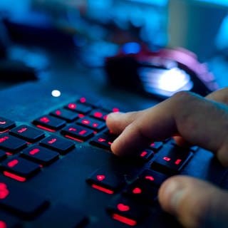 Ein Mann sitzt am Rechner und tippt auf einer Tastatur. Kriminelle Hacker haben Unternehmen und öffentliche Einrichtungen im Visier und drohen oft damit, auch die Daten von unbeteiligten Kunden zu veröffentlichen.