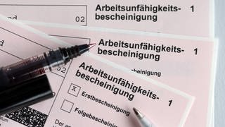 Stifte liegen auf den Arbeitsunfähigkeitsbescheinigungen für Arbeitnehmer im Falle einer Krankschreibung durch den Arzt