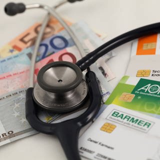 Geld, Krankenkassenkarten und ein Stethoskop 