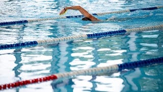 EIn Schwimmer zieht seine Bahnen im Hallenbad.