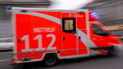 Ein rot-weißer Krankenwagen der Feuerwehr mit der Notrufnummer 112 fährt mit eingeschaltetem Blaulicht schnell durch die Stadt. Symbolbild für Junge muss im Freibad Landau wiederbelebt werden