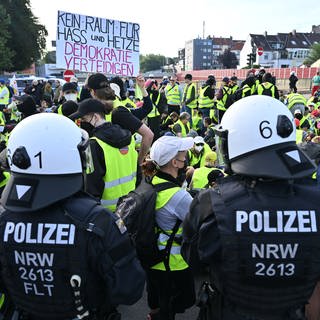 Demonstranten stehen und sitzen auf einer Zufahrtsstraße zum Gelände des AfD-Bundesparteitags in Essen 