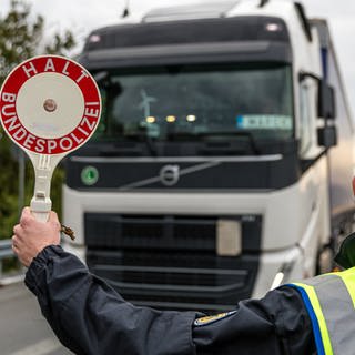 Verkehrspolizist hält Warnkelle raus, um einen LKW für die Personenkontrolle zum Stillstand zu bringen.