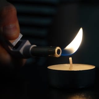 Eine Kerze wird mit einem Feuerzeug angezündet - für den Fall eines Blackouts sollten in jedem Haushalt Kerzen und Streichhölzer vorhanden sein.
