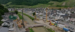Drei Jahre nach der Flutkatastrophe im Ahrtal läuft der Wiederaufbau. Wie hier in Dernau sind oft Baumaschinen, Kräne und Betonmischer im Einsatz.