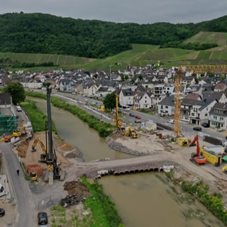 Drei Jahre nach der Flutkatastrophe im Ahrtal läuft der Wiederaufbau. Wie hier in Dernau sind oft Baumaschinen, Kräne und Betonmischer im Einsatz.
