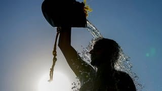 Ein Mann kühlt sich mit einem Eimer Wasser ab. Am Wochenende werden in RLP über 30 Grad erwartet.