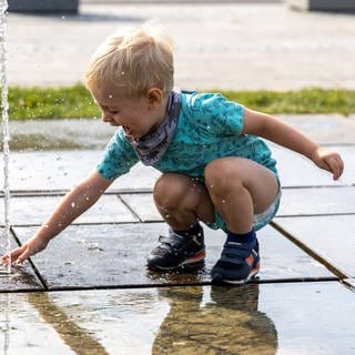 Junge spielt mit Springbrunnen