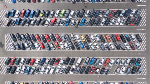 Luftaufnahme von unzähligen Autos, die auf einem riesigen Parkplatz stehen. Wenn es nach der FDP ginge, dann würde es in deutschen Städten wieder mehr Parkplätze für Autos geben.