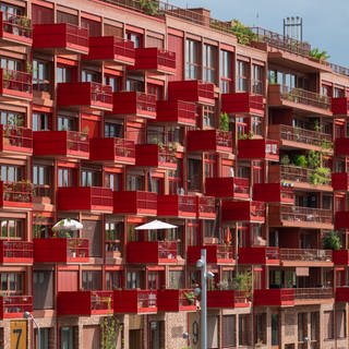 Ein Wohnungsblock mit markanten, roten Balkonen. Wer sich die Miete für seine Wohnung nicht leisten kann, hat die Möglichkeit, Wohngeld zu beantragen.