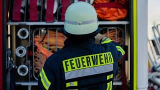 Ein Feuerwehrmann holt sein Equipment aus einem Einsatzfahrzeug. Einen Brand gab auch im Westerwald. Ein Retter wurde dabei verletzt.