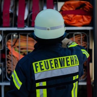 Ein Feuerwehrmann holt sein Equipment aus einem Einsatzfahrzeug. Einen Brand gab auch im Westerwald. Ein Retter wurde dabei verletzt.