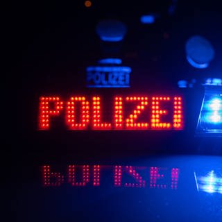 Es ist ein Polizeiauto mit der Leuchtschrift Polizei auf dem Dach zu sehen. 