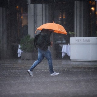 Ein Mann läuft mit einem Regenschirm durch starken Regen. Der Sturm Kirk zog in der Nacht über RLP, doch richtete er nur wenige Schäden an. 