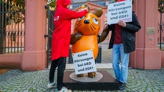 Die Figur der Maus aus der "Sendung mit der Maus" steht zwischen Aktivisten von Campact vor dem Landtag Rheinland-Pfalz.