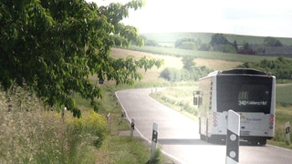 Ein Regionalbus fährt über die Landstraße in Richtung Koblenz. Der Städtetag Rheinland-Pfalz prüft, beim ÖPNV auf dem Land Kosten zu sparen.