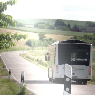 Ein Regionalbus fährt über die Landstraße in Richtung Koblenz. Der Städtetag Rheinland-Pfalz prüft, beim ÖPNV auf dem Land Kosten zu sparen.