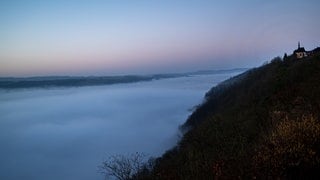 Die Kapelle auf dem Markusberg in Trier ragt bereits aus dem Nebel, unter dem die Stadt und die Mosel noch verborgen sind. Der Nebel hat es der Sonne im Oktober 2024 oft schwer gemacht.