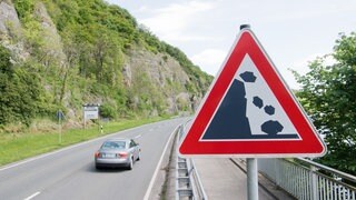 Ein Auto fährt über eine Straße, vorbei an Felsen - in Bingen Büdesheim stürzten Felsbrocken auf Autos