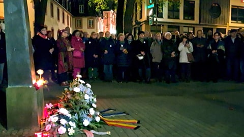 Menschen in Trier umstehen die Gedenkstätte für die Pogromnacht 