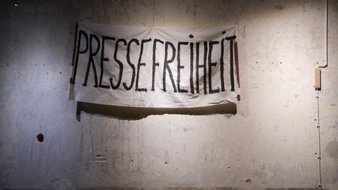  Ein Banner mit der Aufschrift "Pressefreiheit" hängt an einer Betonwand