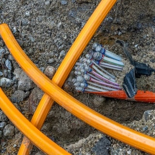 Eine Baustelle, in der ein Glasfaserkabel im Boden verlegt wird. Die Verbraucherzentrale Rheinland-Pfalz gibt Antworten auf die wichtigsten Fragen zum Glasfaserausbau.