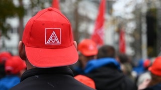 Der Kopf eines Mannes von hinten. Er trägt eine rote Basecap mit dem Logo von "IG Metall". Die Gewerkschaften und die Arbeitgeber haben sich nun auch in Rheinland-Pfalz auf einen Tarifabschluss geeinigt.