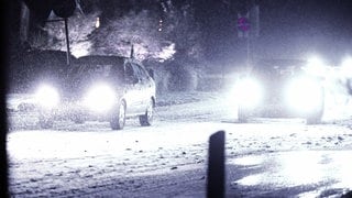 Autos bewegen sich auf einer schneeglatten Straße im Schrittempo voran