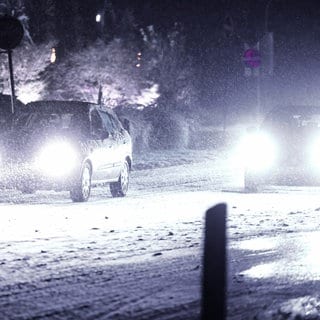 Autos bewegen sich auf einer schneeglatten Straße im Schrittempo voran