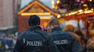 Zwei Polizisten gehen Streife auf einem Weihnachtsmarkt. In diesem Jahr muss auch ein generelles Messerverbot kontrolliert werden.