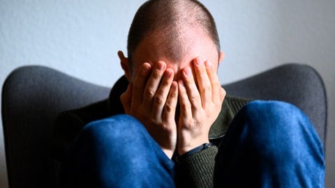 Mann verbirgt sein Gesicht hinter den Händen - immer mehr Männer leiden unter Depressionen