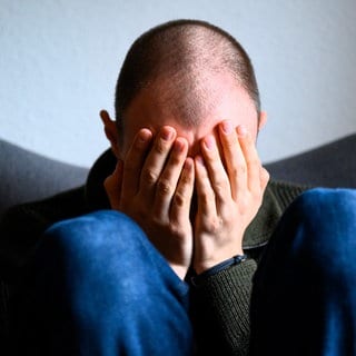 Mann verbirgt sein Gesicht hinter den Händen - immer mehr Männer leiden unter Depressionen