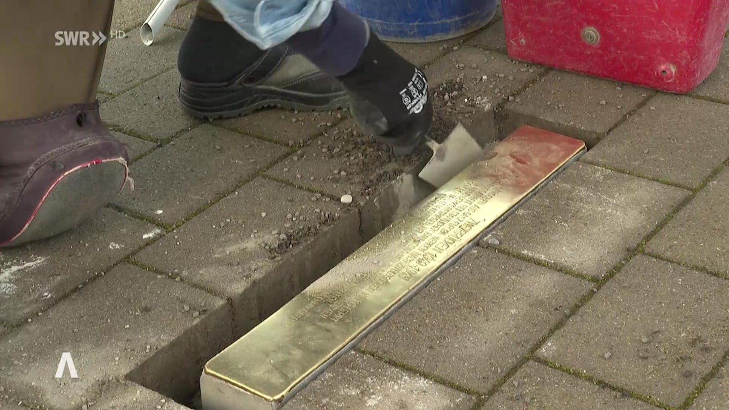 Mann verlegt eine Stolperschwelle zum Gedenken an die Opfer des NS-Regimes