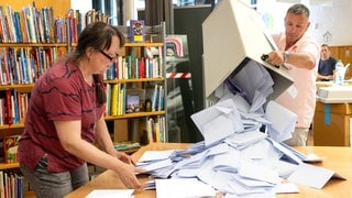 Wahlhelfer leeren die Stimmzettel aus einer Wahlurne. 