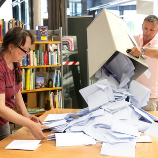 Wahlhelfer leeren die Stimmzettel aus einer Wahlurne. 