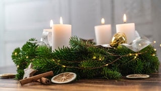 Ein festlicher Adventskranz auf Holz mit brennenden Kerzen zur Adventszeit.