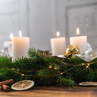 Ein festlicher Adventskranz auf Holz mit brennenden Kerzen zur Adventszeit.