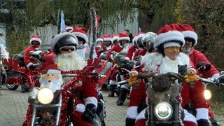 25 Weihnachtsmänner oder Santas sind mit ihren Harley-Davidson-Motorrädern unterwegs und sammeln Spenden.