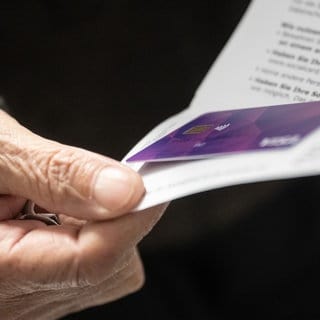 Ein Flüchtling hält eine Bezahlkarte in der Hand. In RLP will das Land die Bezahlkarte zuerst in der Erstaufnahme in Trier einführen.