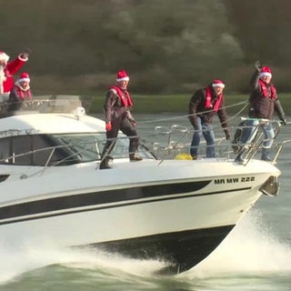 Ein Nikolaus fährt mit anderen Männern auf einer Yacht über einen Fluss