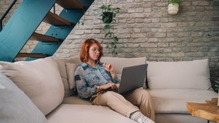 Eine Frau sieht interessiert und nachdenklich in ihr Smartphone.