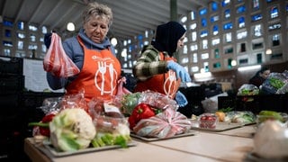 Tafel-Mitarbeiterinnen sortieren die Ware auf Tabletts für die Ausgabe. Auch in Rheinland-Pfalz berichten Tafeln, dass sie mehr Bedürftige versorgen müssten.