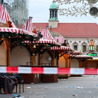 Weihnachtsmarktbuden stehen hinter einer Absperrung auf dem Magdeburger Weihnachtsmarkt. Am Vorabend war ein Autofahrer in eine Menschengruppe gefahren. Es gab mehrere Tote und Verletzte.