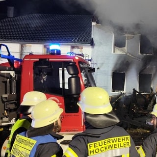 Einsatzkräfte stehen bei den Löscharbeiten in Hockweiler im Kreis Trier-Saarburg vor der Brandruine eines Wohnhauses. 