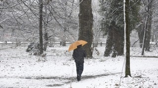 Mann mit einem Regenschirm an einem verschneiten Wintertag 